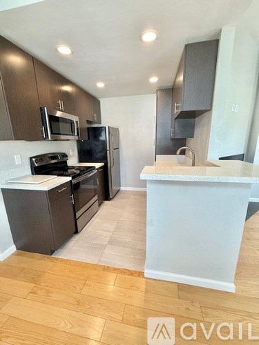 A kitchen with a white counter top and wooden floors.