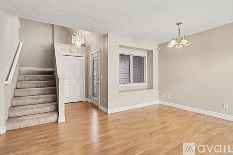 A spacious room with wooden flooring and a staircase leading to another level.