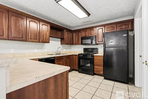 A kitchen with brown cabinets and black appliances.