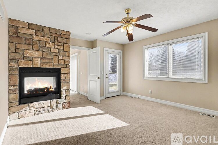 A living room with a stone fireplace and a ceiling fan.