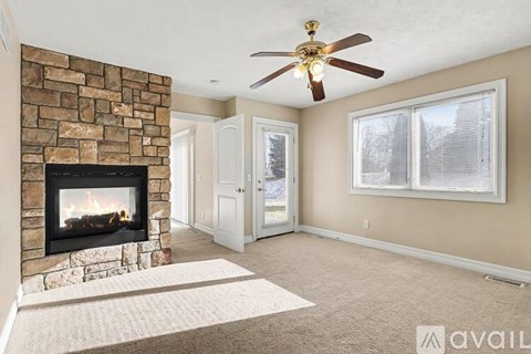 A living room with a stone fireplace and a ceiling fan.