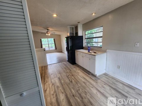 A kitchen with a black refrigerator and white cabinets.