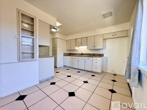 A kitchen with white cabinets and black and white tiled flooring.