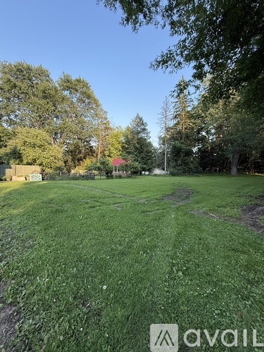 A grassy field with trees and a building in the distance.