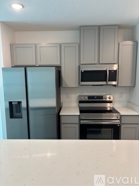 A kitchen with a refrigerator, microwave, oven and cabinets.