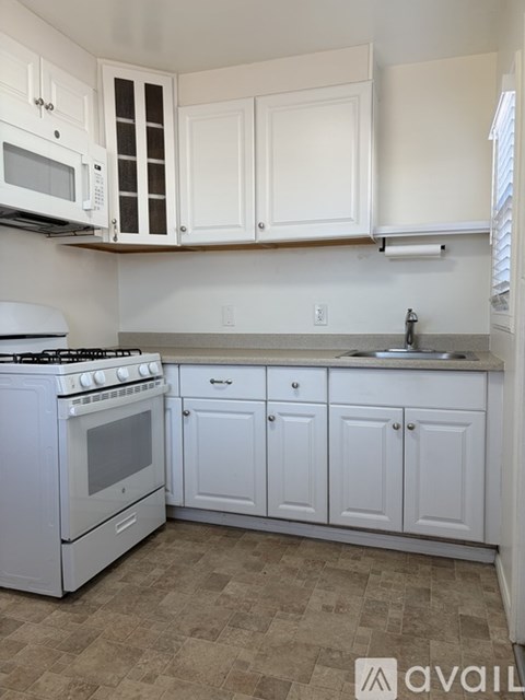 A kitchen with white appliances and cabinets.