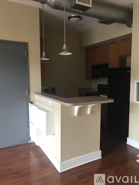 A kitchen with a black refrigerator and wooden floors.
