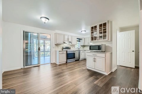 A kitchen with white cabinets and a wooden floor.