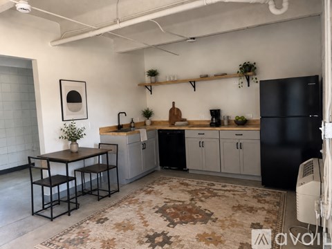 A kitchen with black cabinets and a rug on the floor.