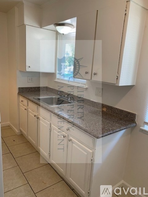A kitchen with white cabinets and a granite countertop.