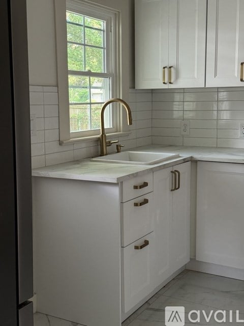 A kitchen with white cabinets and a window.
