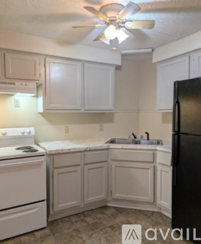 A kitchen with white cabinets and a black refrigerator.
