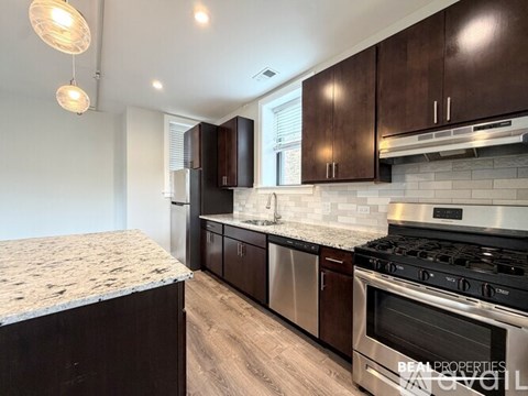 A kitchen with dark wood cabinets and stainless steel appliances.