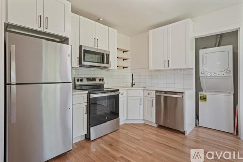 A kitchen with white cabinets and a refrigerator.