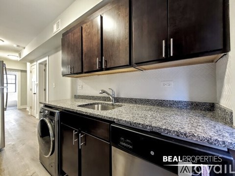 A modern kitchen with dark brown cabinets and a granite countertop.