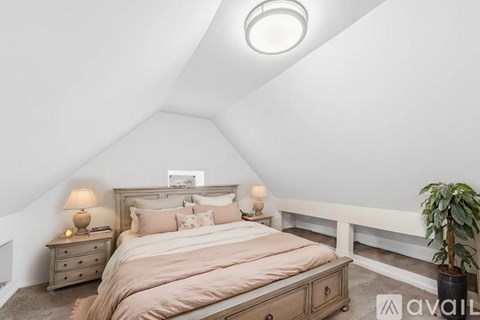 A bedroom with a bed, nightstands, and a plant.