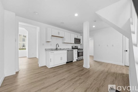 A modern kitchen with white cabinets and a wooden floor.