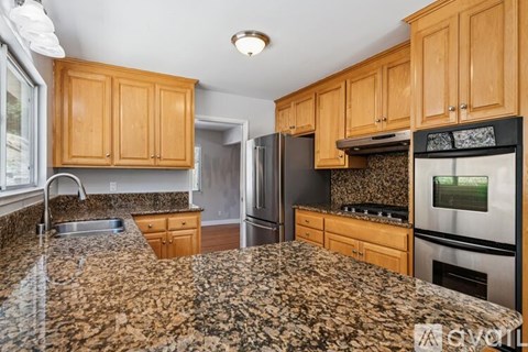 A kitchen with granite countertops and wooden cabinets.