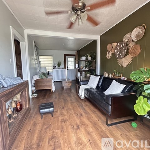 A living room with a black couch and wooden floors.