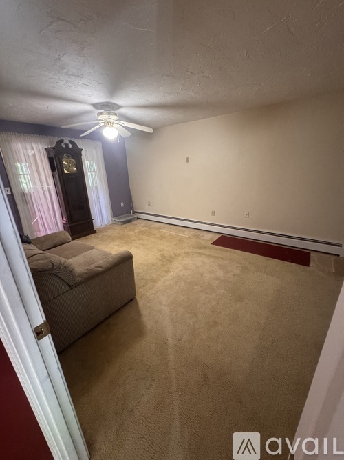 A living room with a couch and a fan.