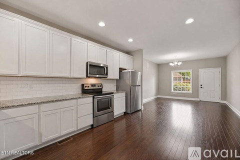 A kitchen with white cabinets and a wooden floor.