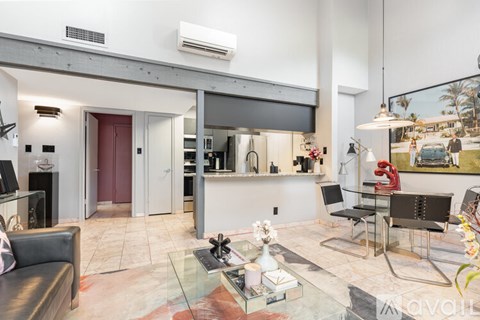 A modern living room with a glass coffee table and a flat screen TV mounted on the wall.
