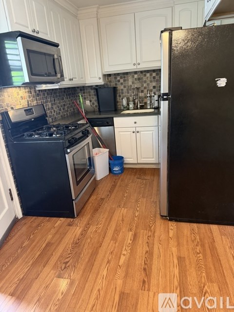 A kitchen with a black fridge and wooden floors.