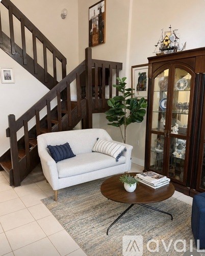 A living room with a white couch and a wooden staircase.
