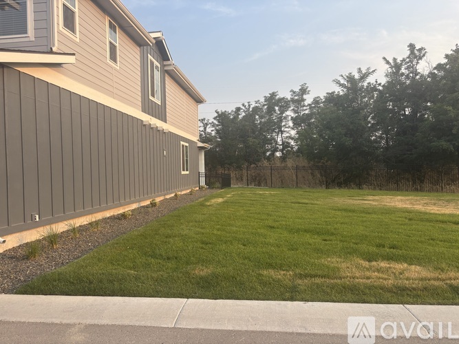 A house with a grey siding and a green lawn.