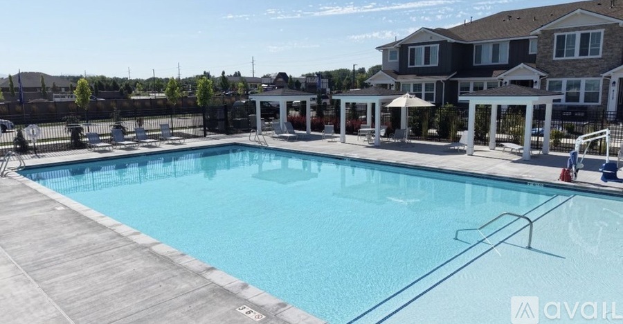 A large swimming pool with a wooden deck and a row of houses in the background.