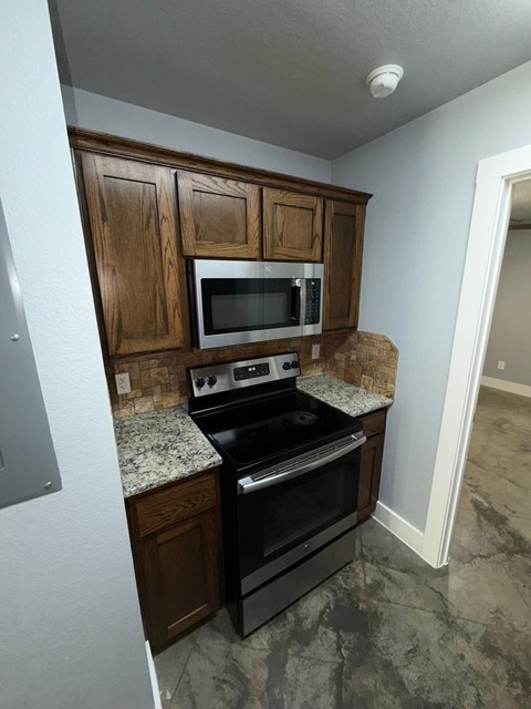 A kitchen with a black stove top oven and microwave above it.