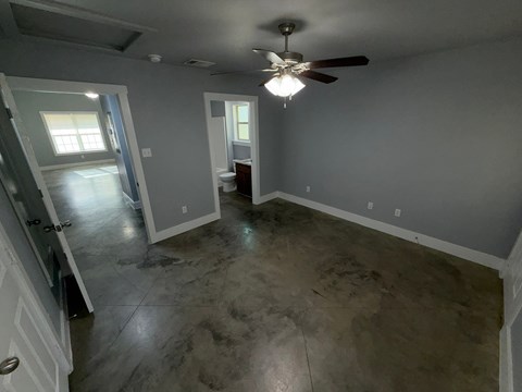 A room with a ceiling fan and a concrete floor.