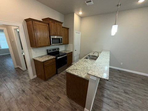 A kitchen with wooden cabinets and a granite countertop.