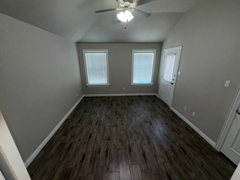 A room with a ceiling fan and wooden flooring.