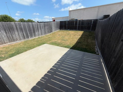 A concrete patio with a black slatted fence in the background.
