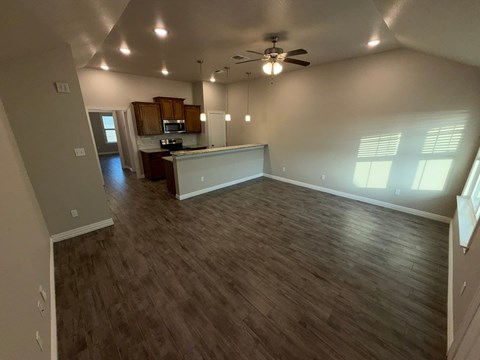 A spacious room with wooden flooring and a ceiling fan.