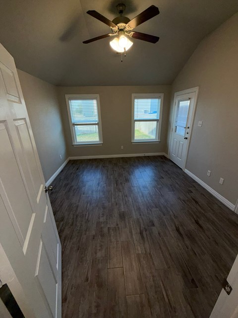A room with a ceiling fan and wooden flooring.