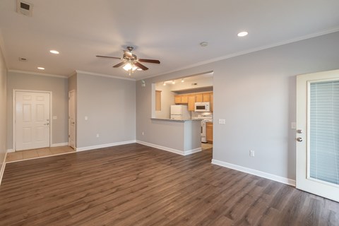 A spacious room with a ceiling fan and wooden flooring.