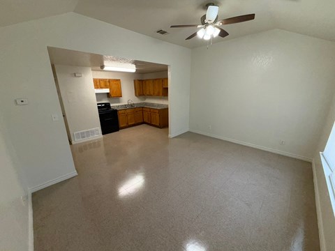 A spacious living room with a kitchen in the background.