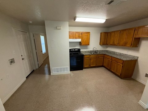 A kitchen with white walls and brown cabinets.