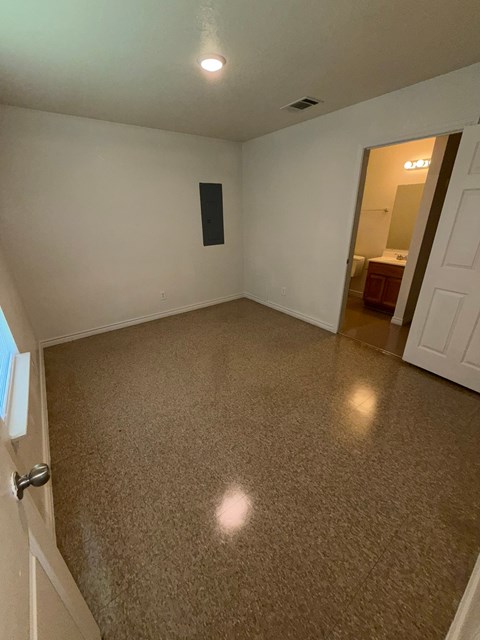 A room with a carpeted floor and a door on the left.