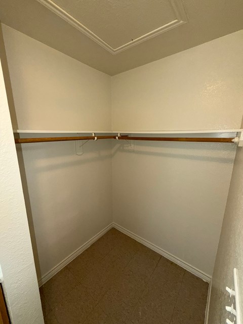 A white closet with a brown shelf and a white door.