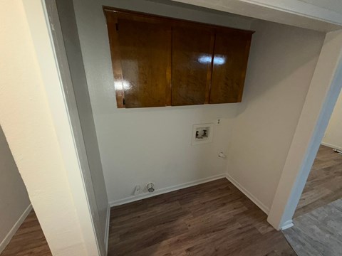 A room with wooden floors and a cabinet above a door.