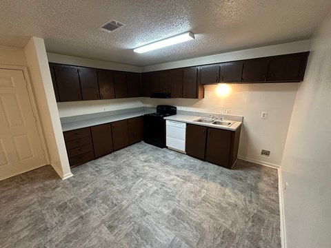 A kitchen with brown cabinets and a black dishwasher.