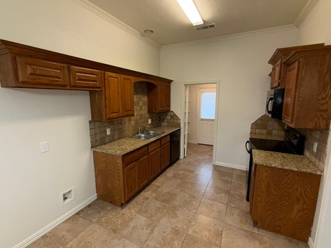 A kitchen with brown cabinets and a granite countertop.