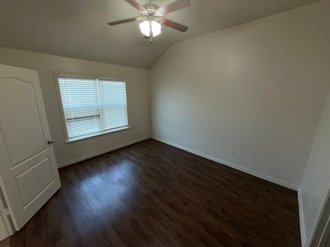 A room with a ceiling fan and a window with blinds.