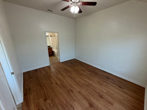 A room with wooden flooring and a ceiling fan.