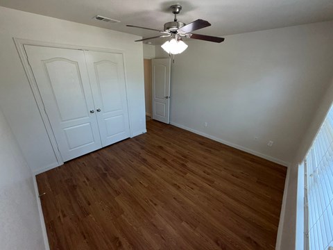A room with a ceiling fan and wooden floors.
