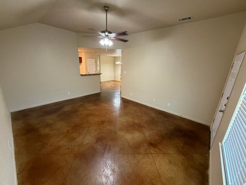 A room with a brown floor and a ceiling fan.