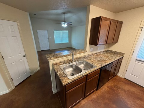A kitchen with brown cabinets and a granite countertop.